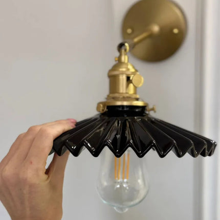 Détail de l'abat-jour plissé en éventail en céramique noire brillante et de la douille en laiton