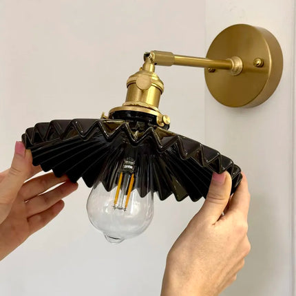 Applique en céramique plissée noire vue de dessus, ampoule à filament allumée sous l'abat-jour