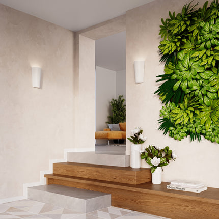 Appliques murales céramique blanche allumées dans un couloir clair, halos chauds sur le mur