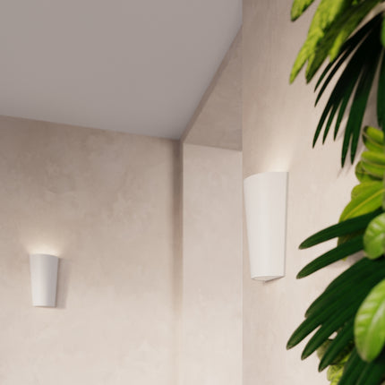 Applique murale céramique blanche près d'un mur végétal, éclairage doux vers le haut