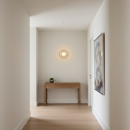 Applique murale ronde allumée dans un couloir d'entrée nordique avec console en bois