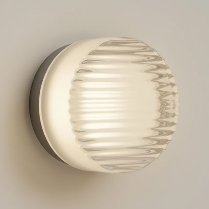 Applique murale ronde en acrylique rainuré allumée sur un mur, diffusant une lumière chaude d'ambiance