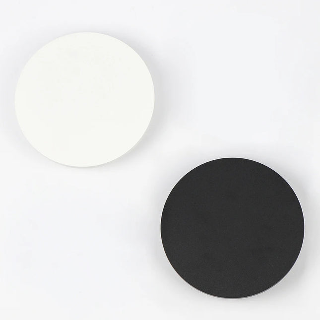 Applique murale ronde en aluminium éclairant un mur de salon en lumière chaude