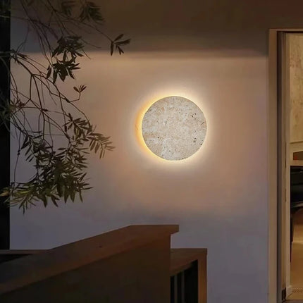 Applique murale ronde en travertin naturel diamètre 23 cm sur un mur clair