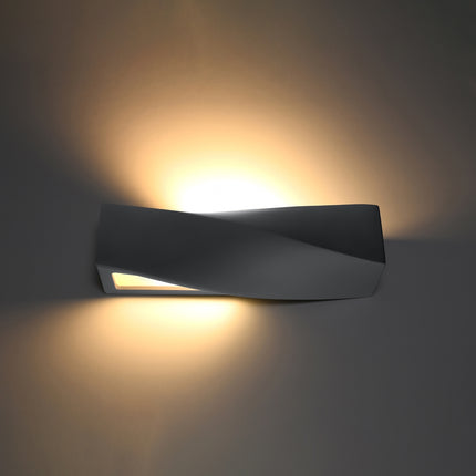 Applique Sigma en céramique grise allumée, double halo de lumière chaude vers le haut et le bas sur un mur foncé