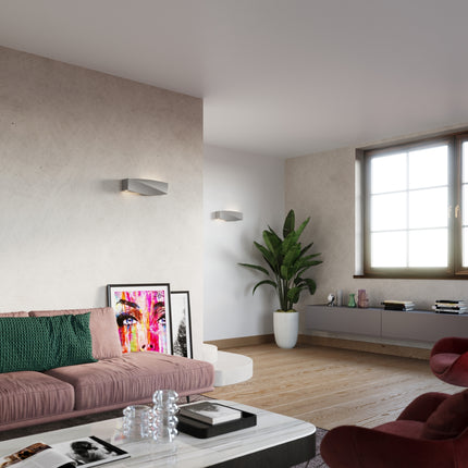 Deux appliques Sigma grises dans un salon contemporain lumineux avec canapé rose et plante