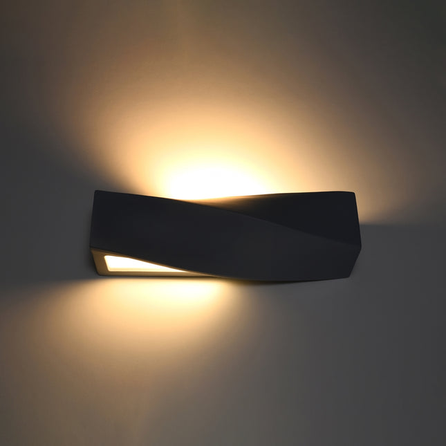 Applique Sigma allumée diffusant une lumière chaude vers le haut et le bas sur un mur