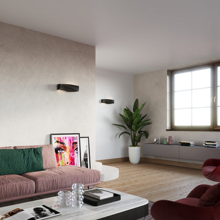 Applique murale Sigma noire au-dessus d'un canapé dans un salon aux murs bruts