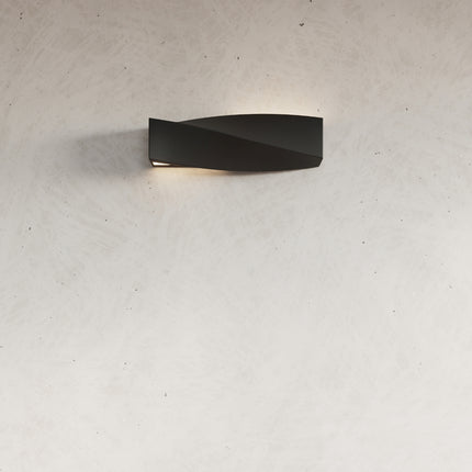 Détail de l'applique Sigma noire allumée sur un mur en béton ciré clair