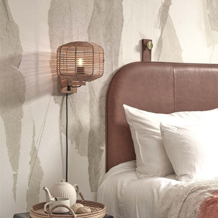 Applique murale Tanami rotin tressé installée au-dessus d'une table de chevet dans une chambre cosy