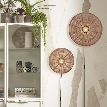 Close-up view of two Tanami braided rattan wall lights on in a natural interior