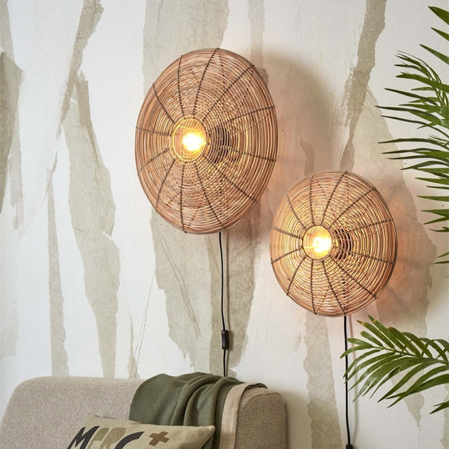 Pair of woven rattan Tanami wall lights lit above a sofa in a bohemian living room