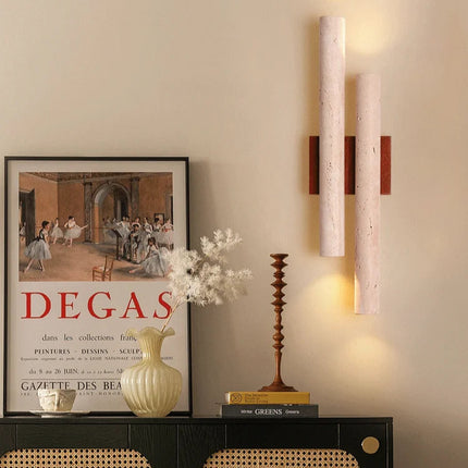 Applique en travertin et bois éclairant un mur beige au-dessus d'un buffet avec vase et affiche encadrée