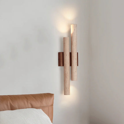 Applique murale en travertin allumée au-dessus d'une tête de lit en cuir dans une chambre épurée
