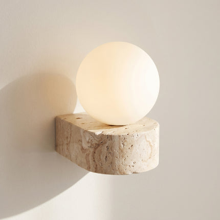 Applique murale travertin naturel et globe opale blanc éclairé sur fond neutre