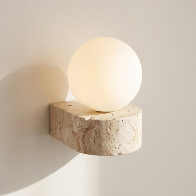 Applique murale travertin naturel et globe opale blanc éclairé sur fond neutre