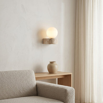 Applique murale travertin globe opale allumée au-dessus d'une console bois dans un salon minimaliste japandi
