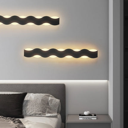 Applique murale LED ondulée noire posée à l'horizontale au-dessus d'une tête de lit dans une chambre