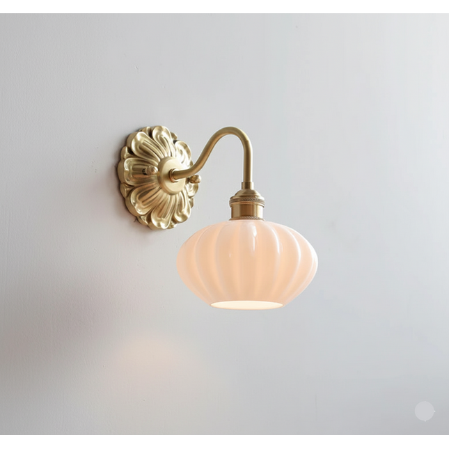 Applique murale vintage, abat-jour en verre opalin rosé côtelé et bras en laiton doré sur un mur clair