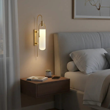 Applique murale dorée en verre opalin allumée en tête de lit dans une chambre chaleureuse