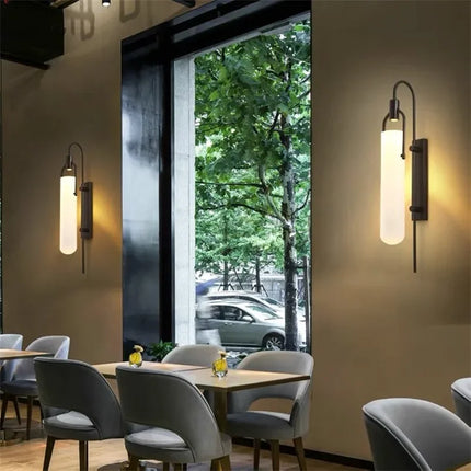 Applique murale en verre opalin et métal noir créant une ambiance tamisée en soirée