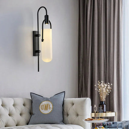 Applique murale noire en verre opalin au dessus d'un canapé beige capitonné dans un salon