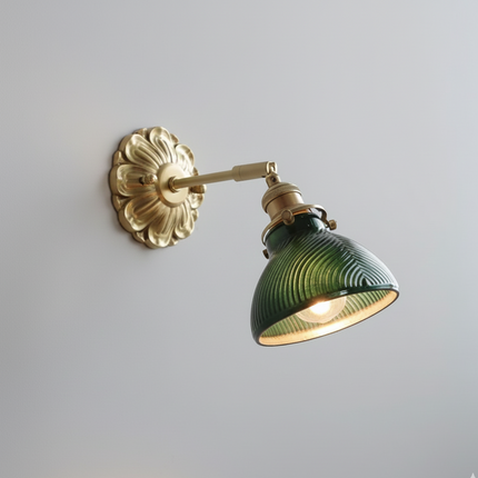 Applique murale vintage en verre vert strié et laiton orientable, allumée sur un mur gris clair