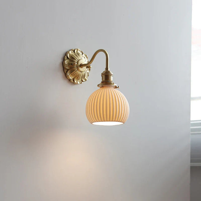 Applique murale vintage à abat-jour boule en céramique striée crème et bras en laiton doré, fixée au mur