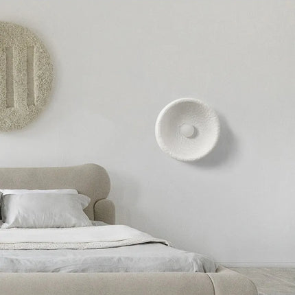 Applique murale Wabi-Sabi blanche texturée au-dessus d'une tête de lit dans une chambre japandi