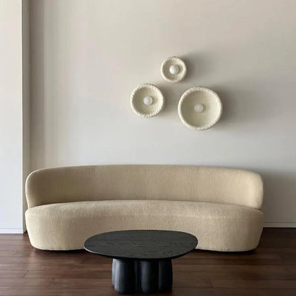 Composition de trois appliques Wabi-Sabi crème au-dessus d'un canapé bouclé dans un salon
