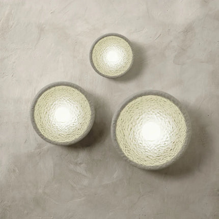 Trio d'appliques murales Wabi-Sabi en résine texturée crème allumées sur un mur en enduit beige