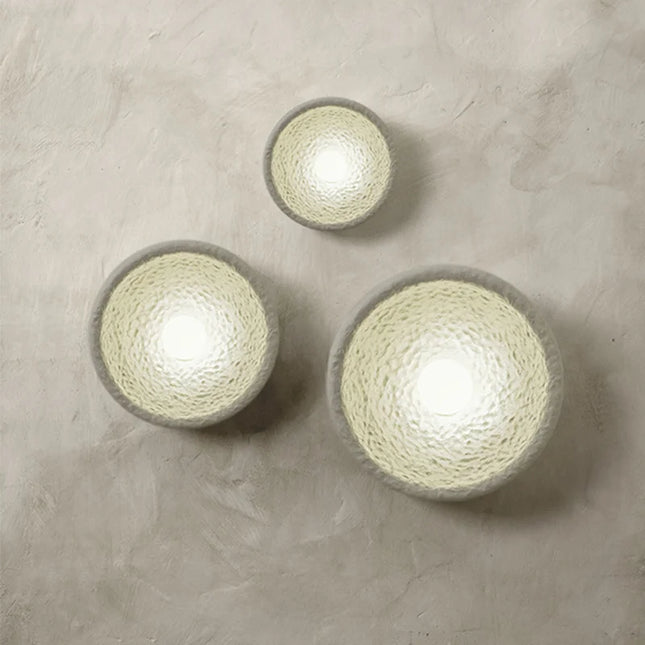 Trio d'appliques murales Wabi-Sabi en résine texturée crème allumées sur un mur en enduit beige