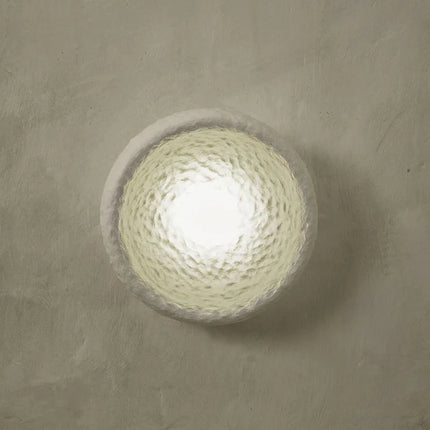 Trio d'appliques Wabi-Sabi blanches texturées sur un mur crème au-dessus d'un banc bouclé