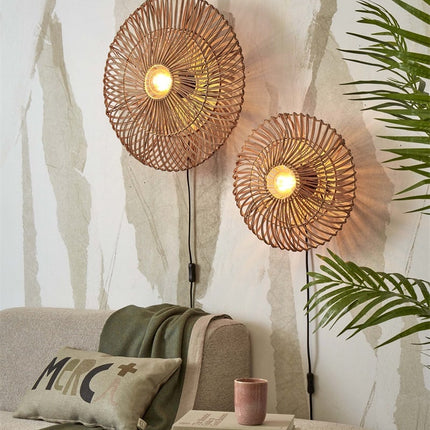Two natural rattan Zanzibar wall lights lit above a sofa, warm boho atmosphere