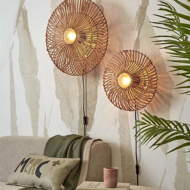 Two natural rattan Zanzibar wall lights lit above a sofa, warm boho atmosphere