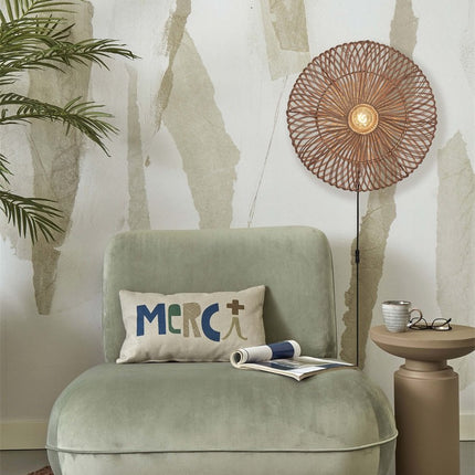 Zanzibar natural rattan wall light switched on near a green armchair and a side table