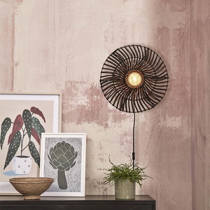 Zanzibar black woven rattan wall light in a lifestyle setting on a low cabinet, warm diffused light