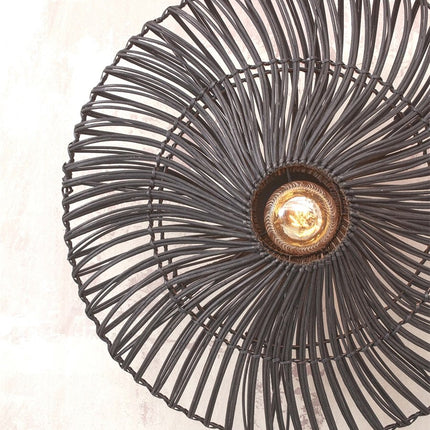 Close-up of the black rattan weave of the round lampshade of the Zanzibar wall light, bulb visible at the center