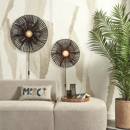 Two black woven rattan Zanzibar wall lights of different sizes above a beige sofa