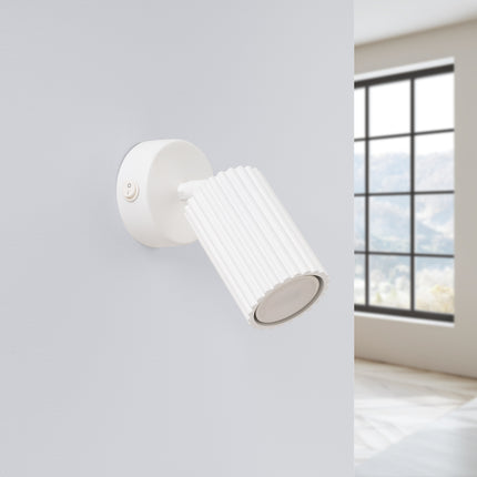 Applique Oslo blanche orientable fixée au mur d'une chambre épurée, près d'une fenêtre