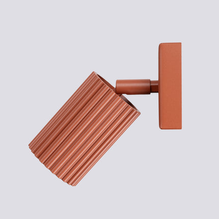 Gros plan sur la tête cylindrique striée rouge ocre de l'applique Oslo et son ouverture pour ampoule GU10