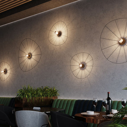 Grandes appliques circulaires filaires noires allumées sur un mur de restaurant chaleureux