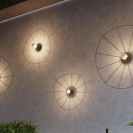 Appliques circulaires filaires noires sur un mur béton, ambiance restaurant chaleureuse