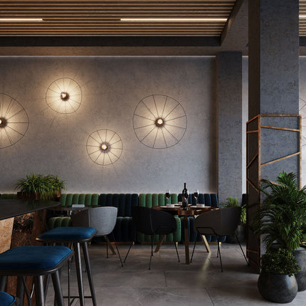 Appliques plafonniers circulaires filaires noirs sur un mur de restaurant contemporain