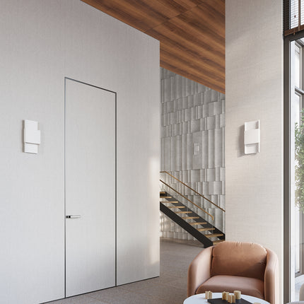 Deux appliques murales blanches encadrant une porte, éclairage d'ambiance dans une entrée design