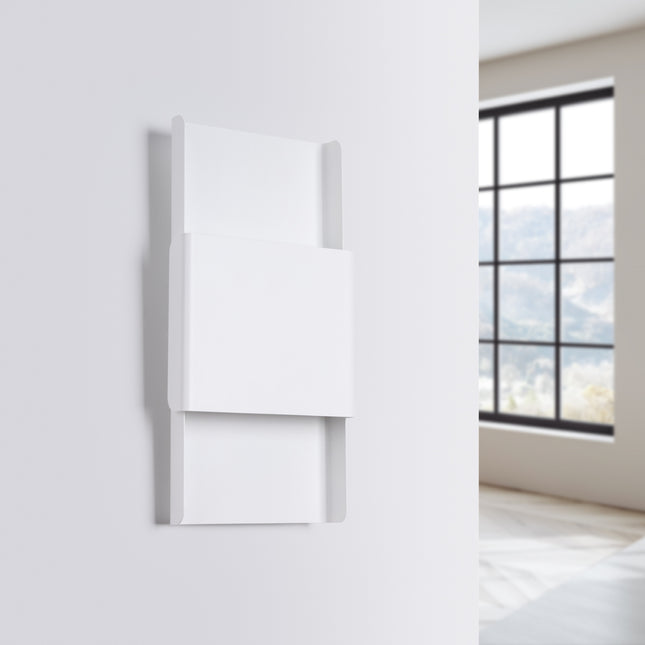 Applique murale design blanche fixée sur un mur clair, vue de biais, ambiance lumineuse douce