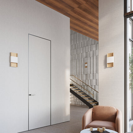 Deux appliques murales or et blanc encadrant une porte, éclairage d'ambiance dans une entrée design