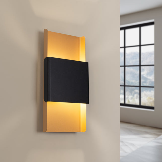 Applique murale or et noir installée sur un mur beige, éclairage chaleureux dans une chambre