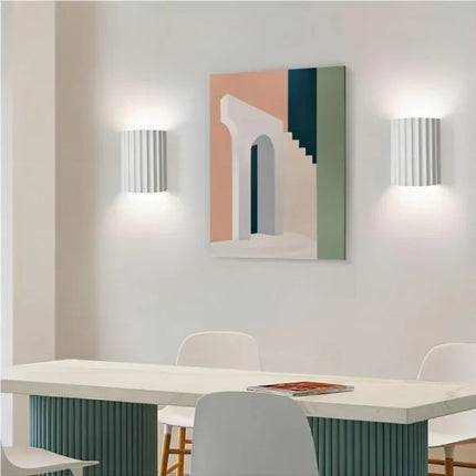 Deux appliques murales en résine cannelée blanches encadrant un tableau au-dessus d'une table de salle à manger