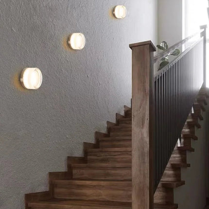 Applique ronde LED à lumière chaude allumée au-dessus d'un chevet dans une chambre nordique